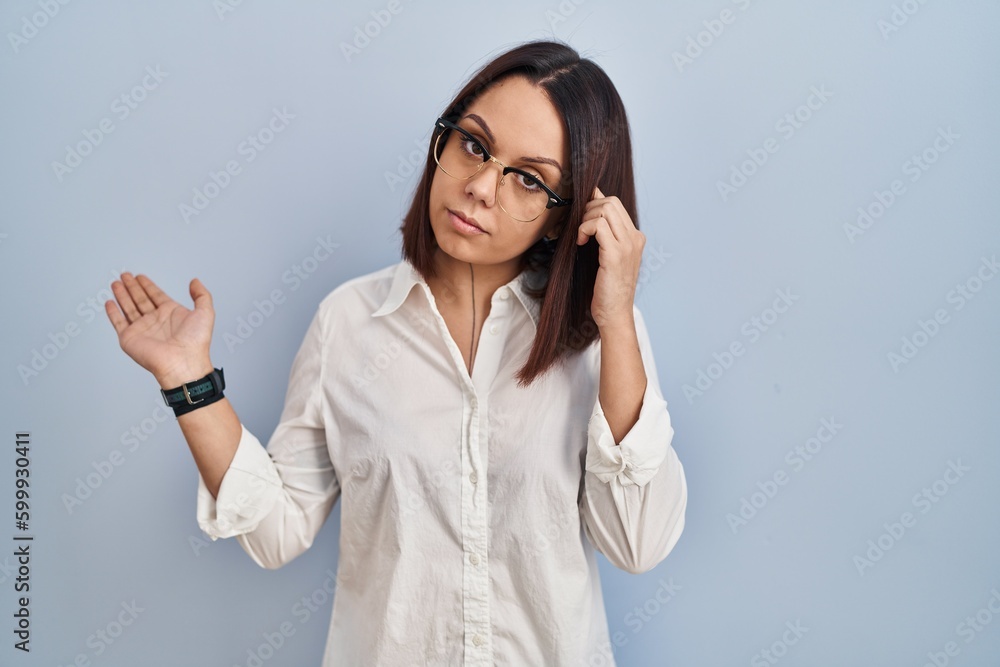 Young hispanic woman standing over white background confused and annoyed with open palm showing copy space and pointing finger to forehead. think about it. Young hispanic woman standing over white background confused and annoyed with open palm showing copy space and pointing finger to forehead. think about it.