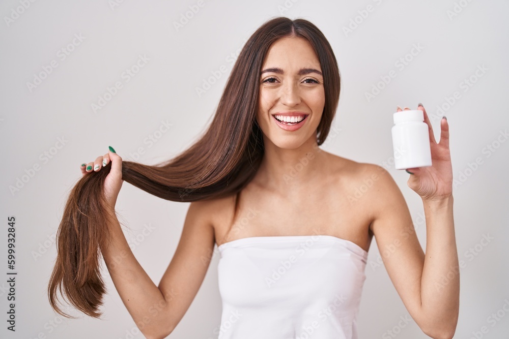 Young hispanic woman holding hair with hand and pills smiling and laughing hard out loud because funny crazy joke. Young hispanic woman holding hair with hand and pills smiling and laughing hard out loud because funny crazy joke.