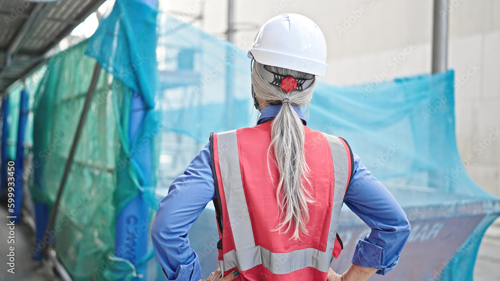 Middle age grey-haired woman builder standing backwards at street Middle age grey-haired woman builder standing backwards at street