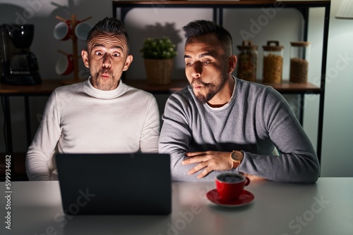 Homosexual couple using computer laptop making fish face with lips, crazy and comical gesture. funny expression.