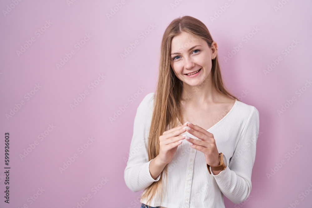 Young caucasian woman standing over pink background hands together and fingers crossed smiling relaxed and cheerful. success and optimistic Young caucasian woman standing over pink background hands together and fingers crossed smiling relaxed and cheerful. success and optimistic