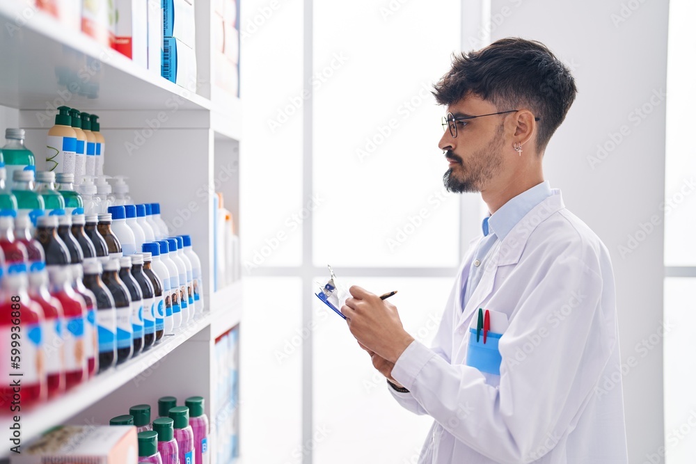 Young hispanic man pharmacist smiling confident writing on document at pharmacy