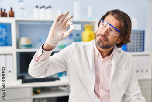 Middle age man scientist holding sample at laboratory