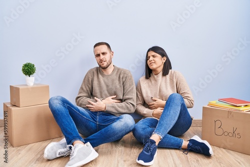 Young couple moving to a new home with hand on stomach because indigestion, painful illness feeling unwell. ache concept. © Krakenimages.com