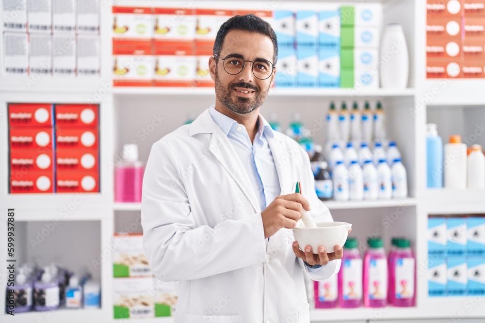 Young hispanic man pharmacist smiling confident working at pharmacy