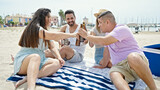 Group of people smiling confident toasting with bottle of beer at beach