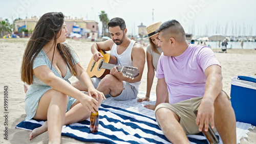 Group of people playing guitar drinking beer singing song at beach