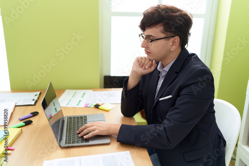 Non binary man business worker using laptop with relaxed expression at office