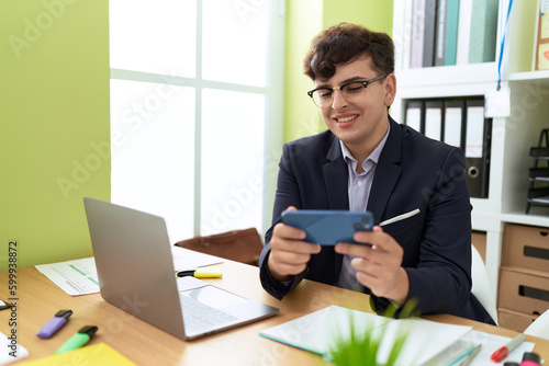 Non binary man business worker using laptop and smartphone at office