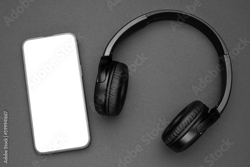 Mockup display. Mobile cell phone blank screen. Black headphones for listening audio music. Smartphone technology. Office workplace. Smart phone. Mock up device for application, website design project