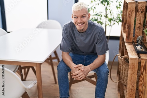 Young caucasian man smiling confident sitting on chair at home