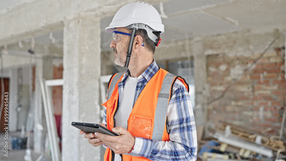 Middle age man builder using touchpad at construction site Middle age man builder using touchpad at construction site
