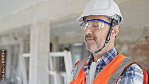 Middle age man builder standing with arms crossed gesture and relaxed expression at construction site
