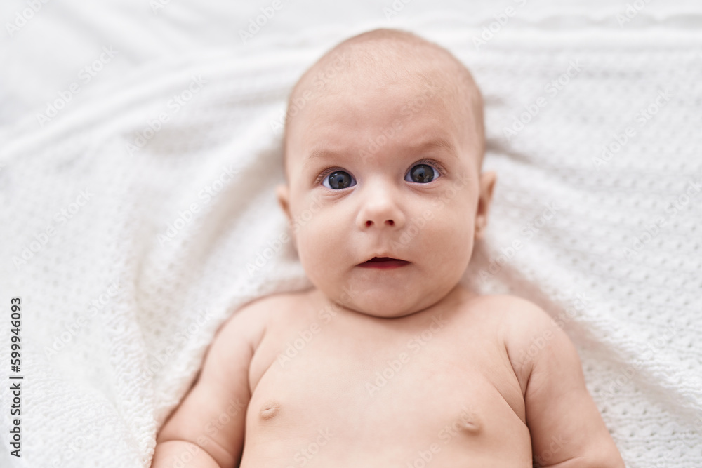 Adorable caucasian baby lying on bed with relaxed expression at bedroom Adorable caucasian baby lying on bed with relaxed expression at bedroom