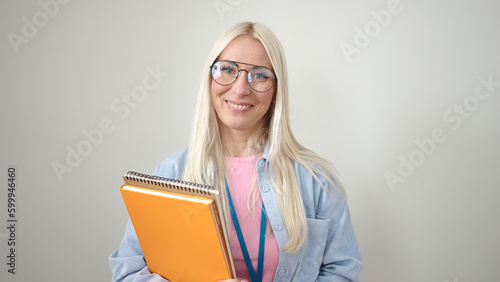 Young blonde woman preschool teacher smiling confident holding books over isolated white background