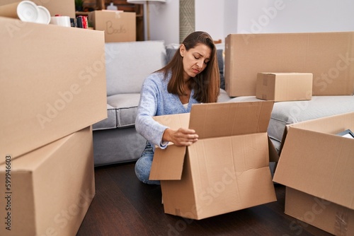 Young woman moving to a new home looking inside cardboard box skeptic and nervous, frowning upset because of problem. negative person. © Krakenimages.com