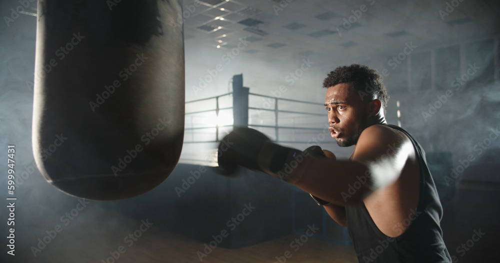 Close up. Handsome african athlete training in a gym, doing a shadow kickboxing art, getting ready for a fight - martial arts, sports concept 