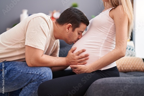Man and woman couple kissing belly sitting on sofa at home