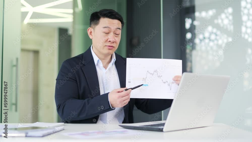 Manager conducts an online presentation via video call using a laptop while sitting in a modern office. A man in a formal suit demonstrates a chart, talking about the corporation's achievements Manager conducts an online presentation via video call using a laptop while sitting in a modern office. A man in a formal suit demonstrates a chart, talking about the corporation's achievements