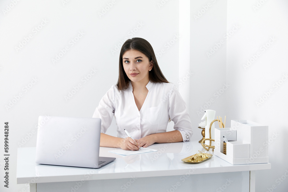Portrait of female doctor talking to online patient on laptop screen sitting at clinic office desk giving online consultation for domestic health treatment Portrait of female doctor talking to online patient on laptop screen sitting at clinic office desk giving online consultation for domestic health treatment