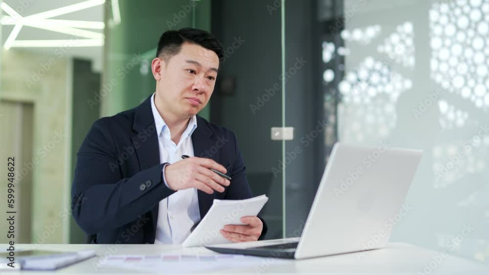 Serious coach in formal suit conducts online training via video call using laptop while sitting at desk at workplace in modern office. Expert teacher communicates on webinar, remote e-learning Serious coach in formal suit conducts online training via video call using laptop while sitting at desk at workplace in modern office. Expert teacher communicates on webinar, remote e-learning