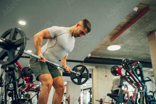 A strong muscular sportsman is doing deadlifts in a gym.