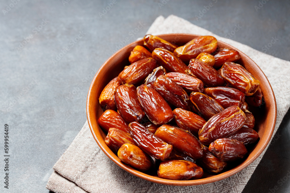Delicious dried dates on a plate. Pitted dates on a dark background. Dried fruits for a healthy diet Delicious dried dates on a plate. Pitted dates on a dark background. Dried fruits for a healthy diet