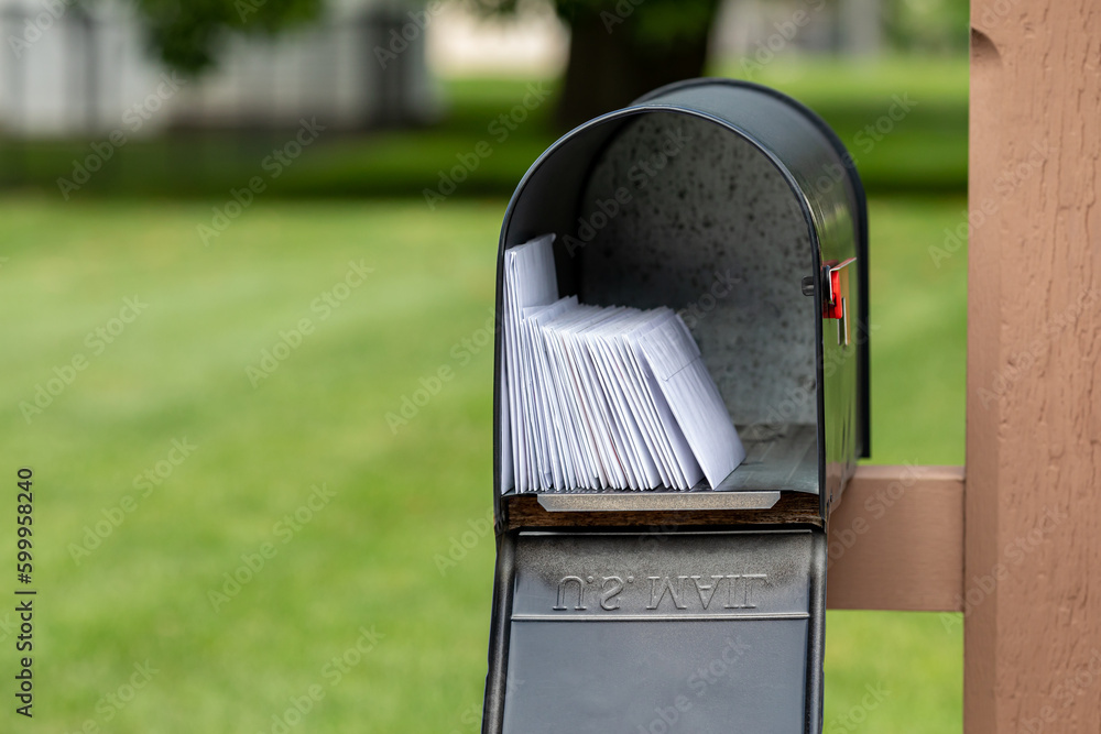 Mailbox full of letters and junk mail. Mail delivery, post office and postal service concept. - obrazy, fototapety, plakaty 