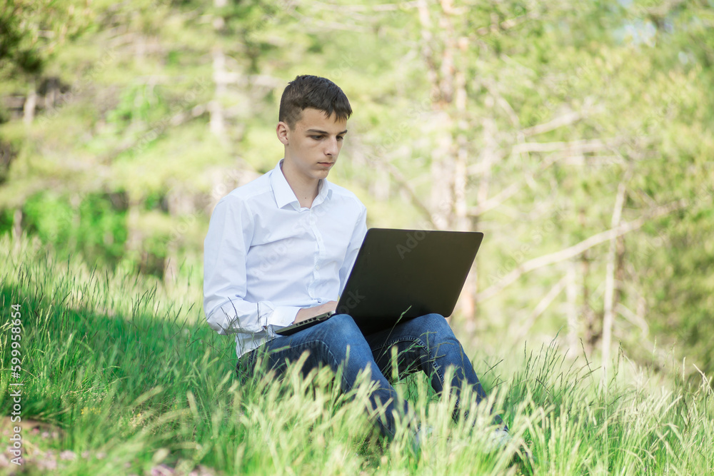 young man sits in the park and works on a laptop young man sits in the park and works on a laptop