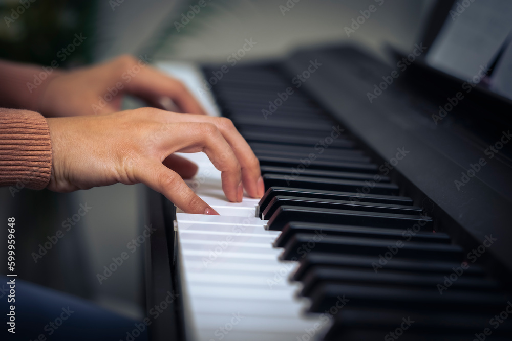 Croped Woman hand press key on piano with little finger and blue living room.