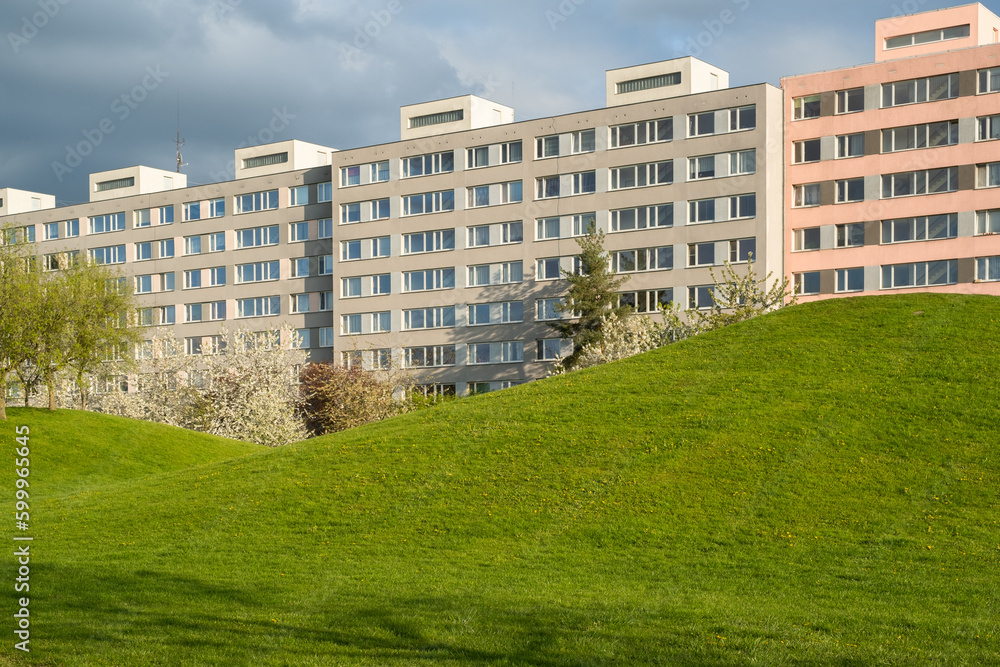 Green spring public park against Typical Modern panel apartment building with plastic windows and thermo insulated walls.  Architecture in West Europe. Insulated exterior wall on buildings with window