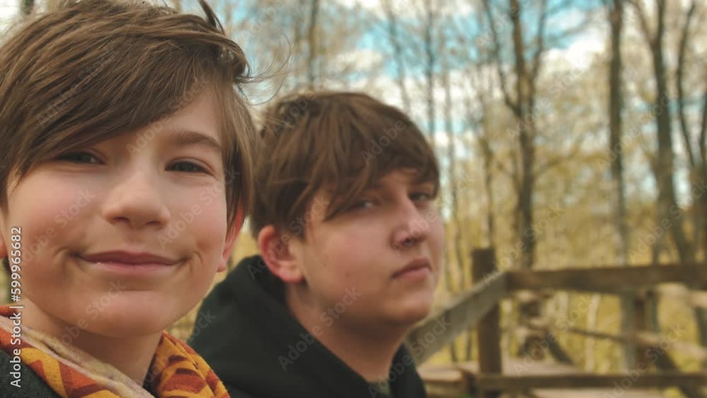 Little brother takes a selfie with big brother. Friends spend time together in spring. The guys are smiling at the camera. Children spend time alone outside. Soft selective focus. Little brother takes a selfie with big brother. Friends spend time together in spring. The guys are smiling at the camera. Children spend time alone outside. Soft selective focus.