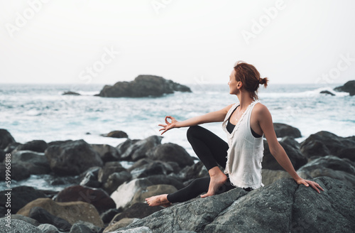 Woman practicing yoga on the beach. Active Travel Healthy Yoga Lifestyle. © nataliaderiabina