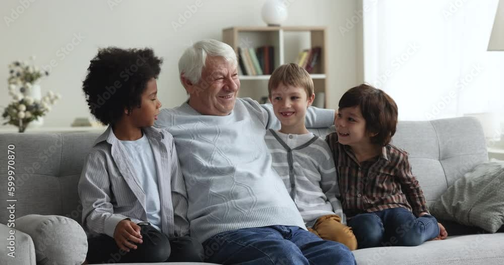 Multiethnic team of happy little diverse boys visiting elder mature retired grandpa, sitting on sofa together, talking, chatting, laughing, enjoying family meeting, leisure time Multiethnic team of happy little diverse boys visiting elder mature retired grandpa, sitting on sofa together, talking, chatting, laughing, enjoying family meeting, leisure time