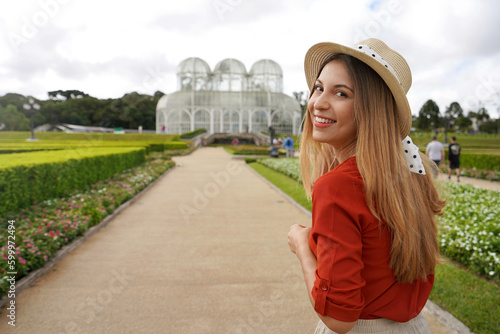 Portrait of happy smiling woman with hat walking in the Botanical Garden of Curitiba turns to the camera, Curitiba, Parana, Brazil photo
