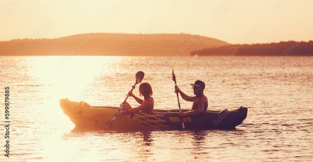 Two rowers on inflatable kayak rowing by the evening sunset rays Adriatic sea harbor in Croatia near Sibenik city. Vacation, sports, and a recreation concept image.. - obrazy, fototapety, plakaty 