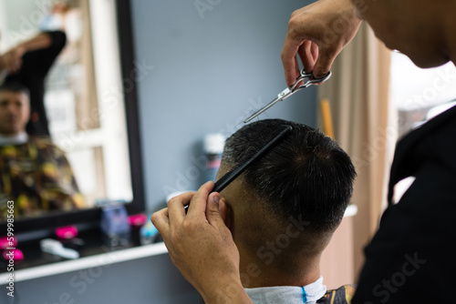 Barber's hands cutting a man's hair. Rear view