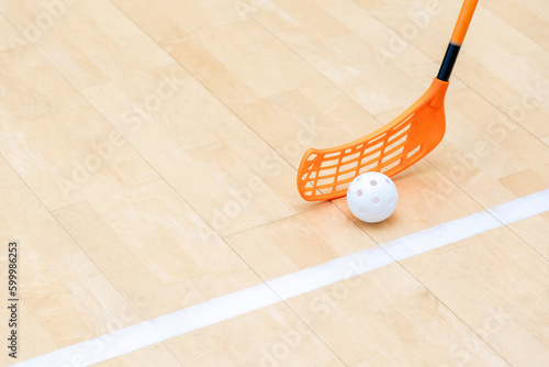 Floorball stick and white ball on hardwood court floor. Horizontal sport theme poster, greeting cards, headers, website and app