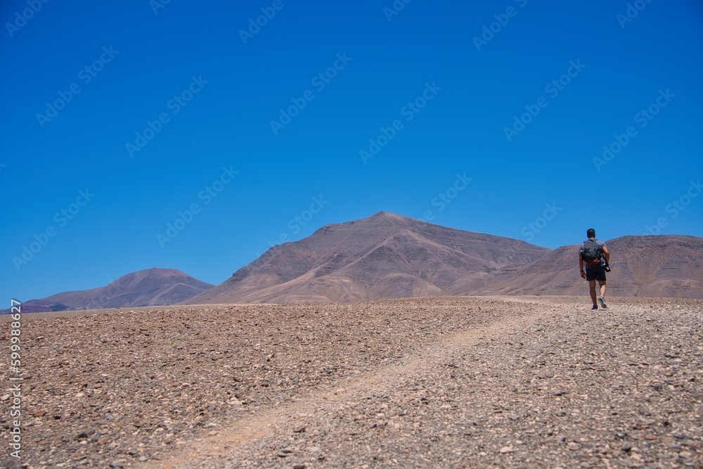 Man walking in the desert between volcano. Copy space.