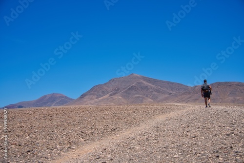 Man walking in the desert between volcano. Copy space.