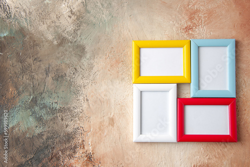 Close up view of colorful picture frames hanging on nude color wall with free space