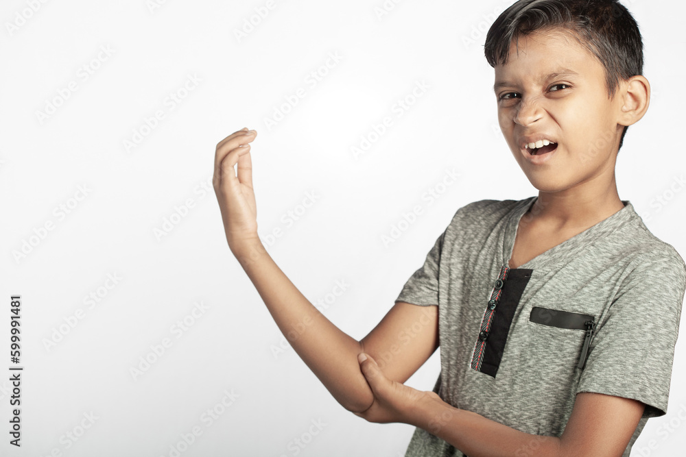 indian boy with painful grimace expression holding his elbow joint injury area in white background indian boy with painful grimace expression holding his elbow joint injury area in white background