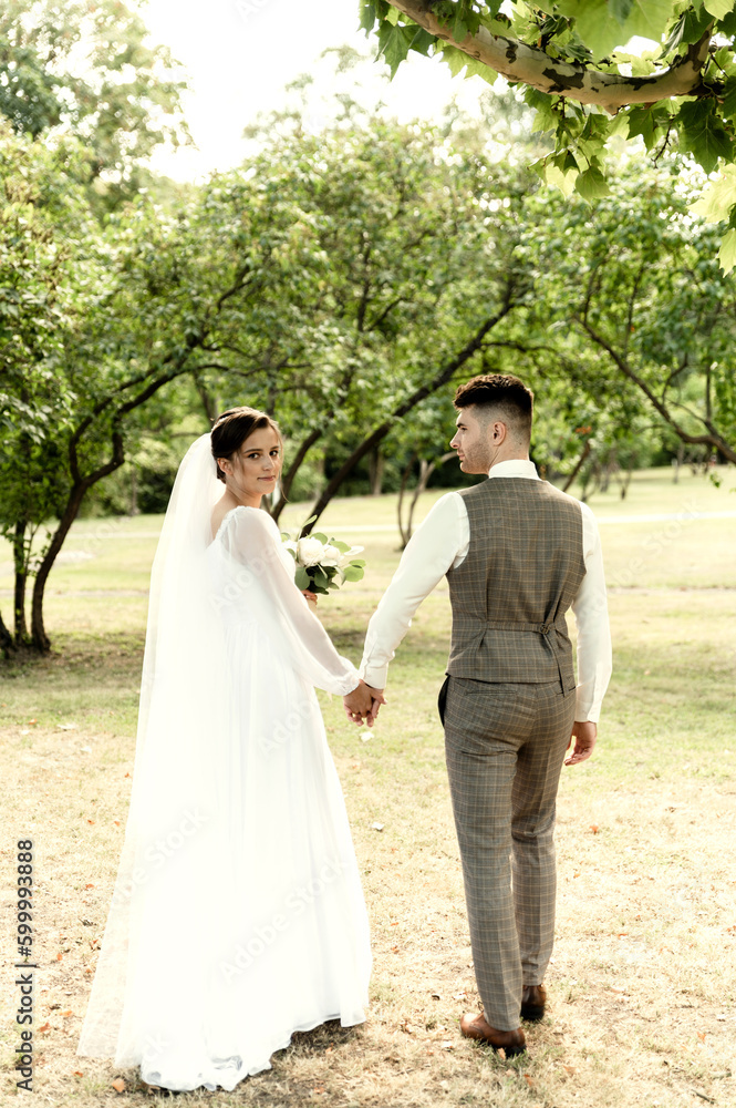 wedding couple in the park, European bride and groom hold hands in the park, happy bride and groom in the park on their wedding day wedding couple in the park, European bride and groom hold hands in the park, happy bride and groom in the park on their wedding day