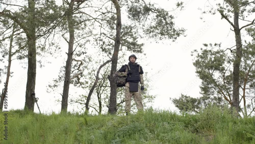 Demining. Soldier with a backpack walks near the trees. Neutralizing mines, soldier removes mines, examining territory Demining. Soldier with a backpack walks near the trees. Neutralizing mines, soldier removes mines, examining territory