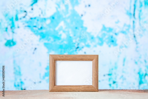 Top view of brown empty picture frame standing on table on pastel blue white mix color background