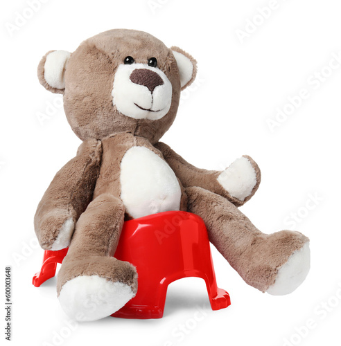 Teddy bear on red baby potty, white background. Toilet training