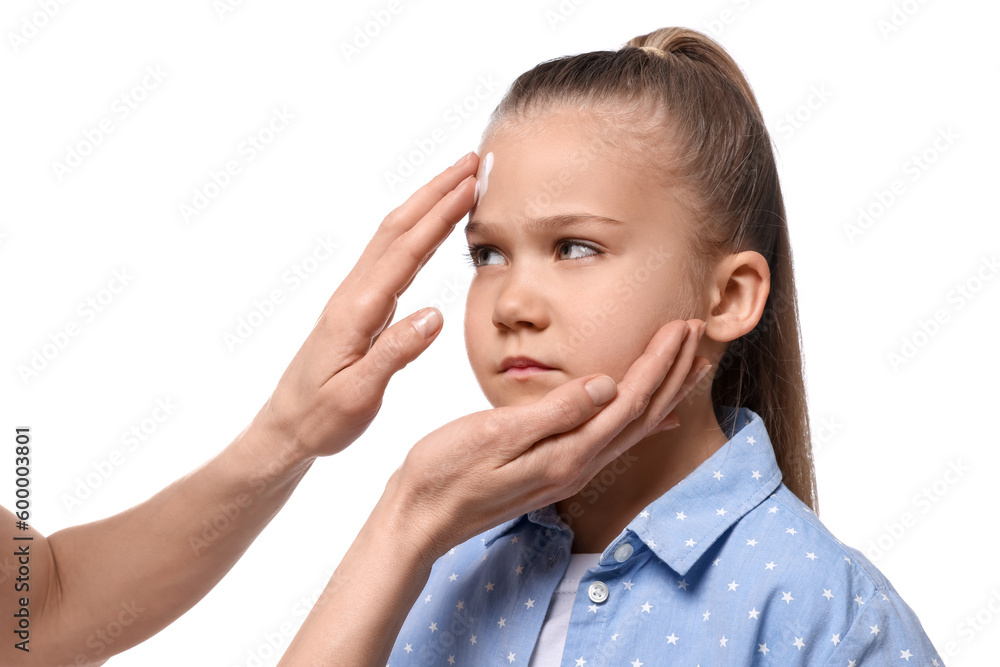 Mother applying ointment on her daughter's forehead against white background Mother applying ointment on her daughter's forehead against white background