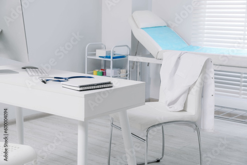 Fototapeta Naklejka Na Ścianę i Meble -  White doctor's gown hanging on chair in clinic