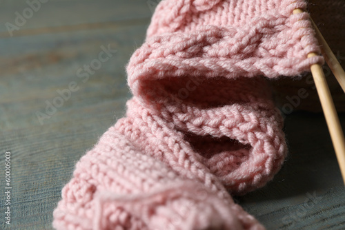 Pink knitting and needles on wooden table, closeup