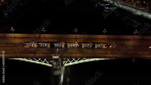 Aerial view of Budapest Margaret Bridge or Margit hid over River Danube, embankment at night. Public transport in the city. Yellow tram passing through the bridge